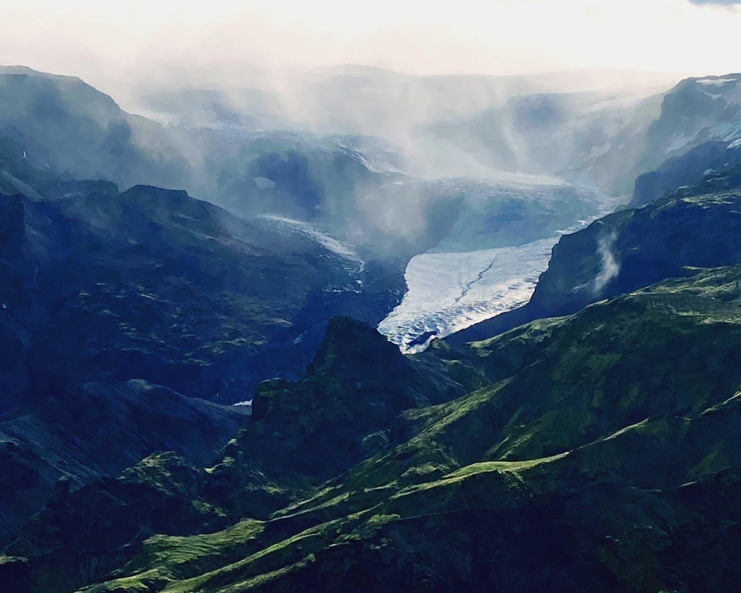 Misty green gorge with a glacial river winding far below in the vast Icelandic highlands